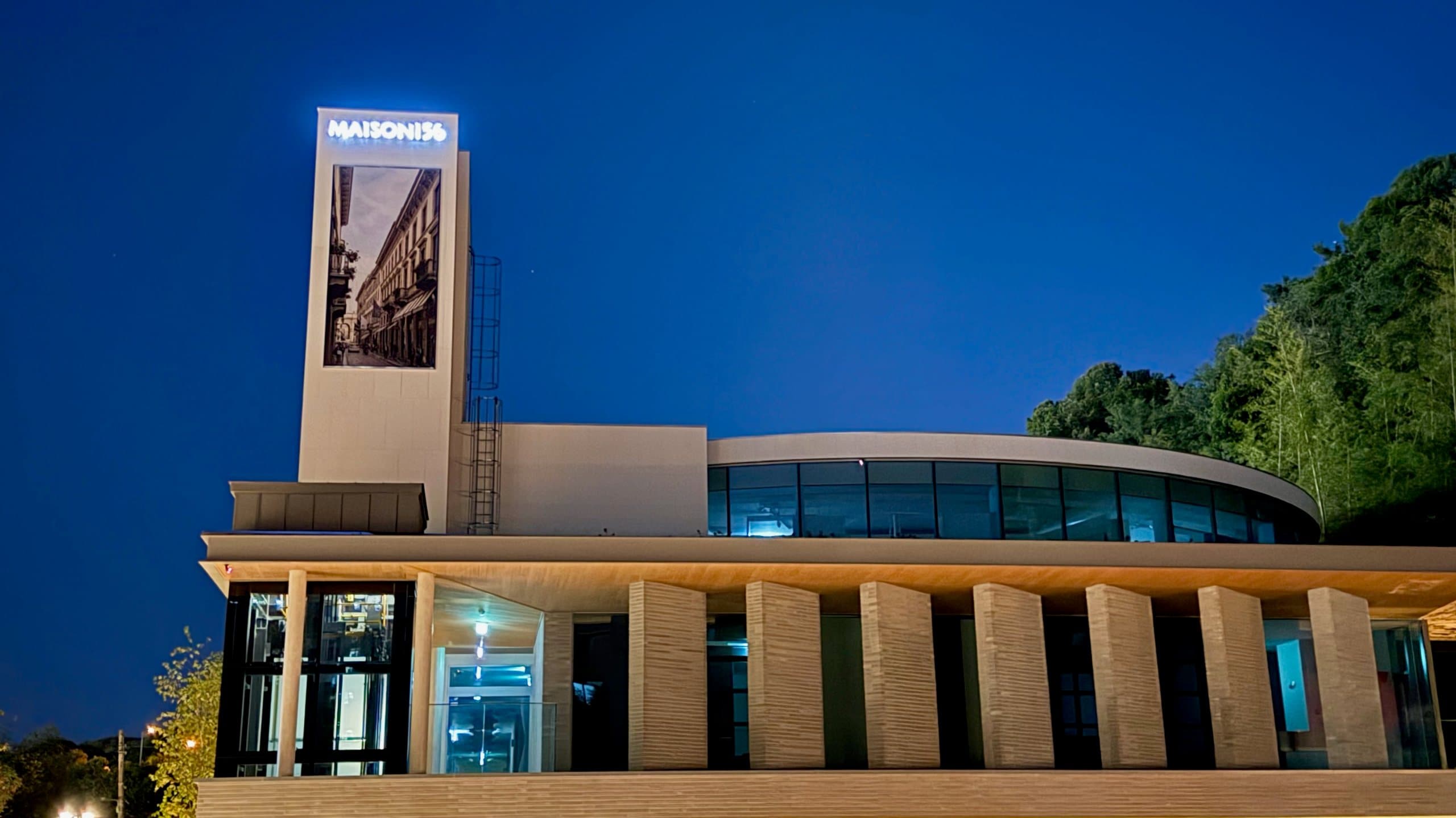 MAISON 156 at blue hour, the illuminated tower and curved glass pavilion