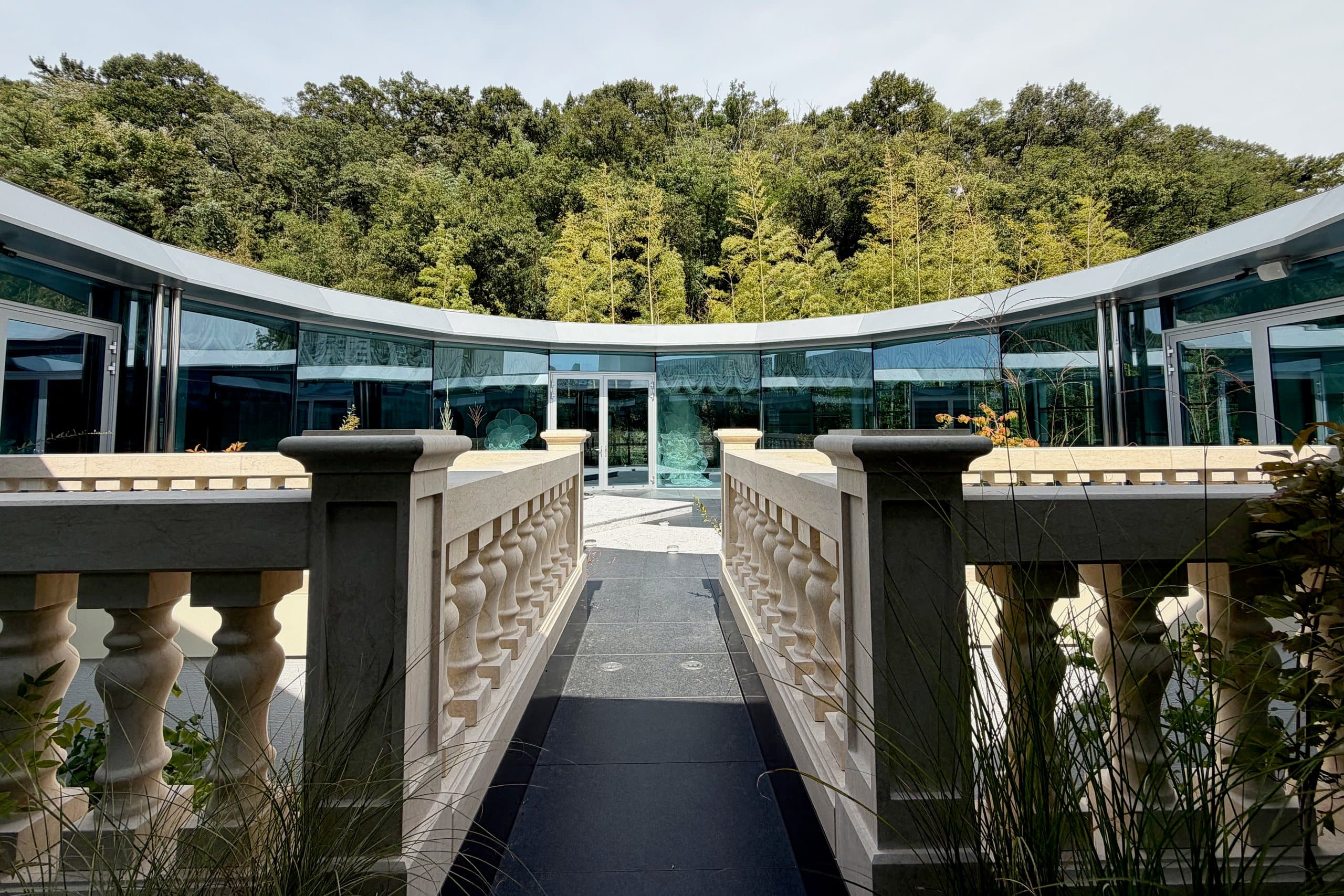 A balustraded bridge leading to the circular glass pavilion