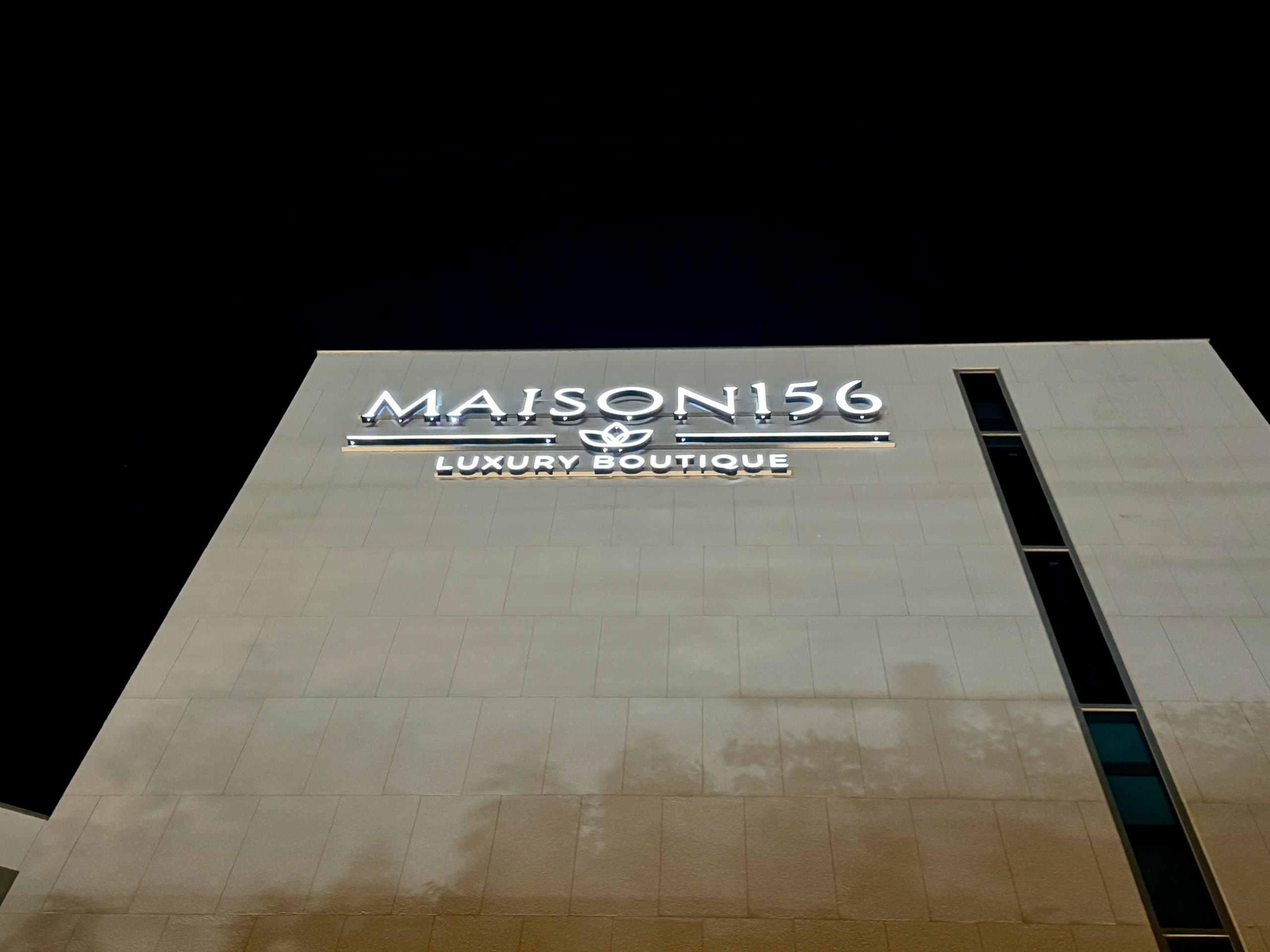 The illuminated MAISON 156 signage at night